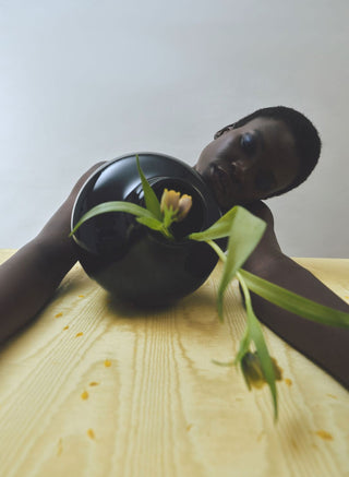 Model looking at tipped-over vase with flower 
